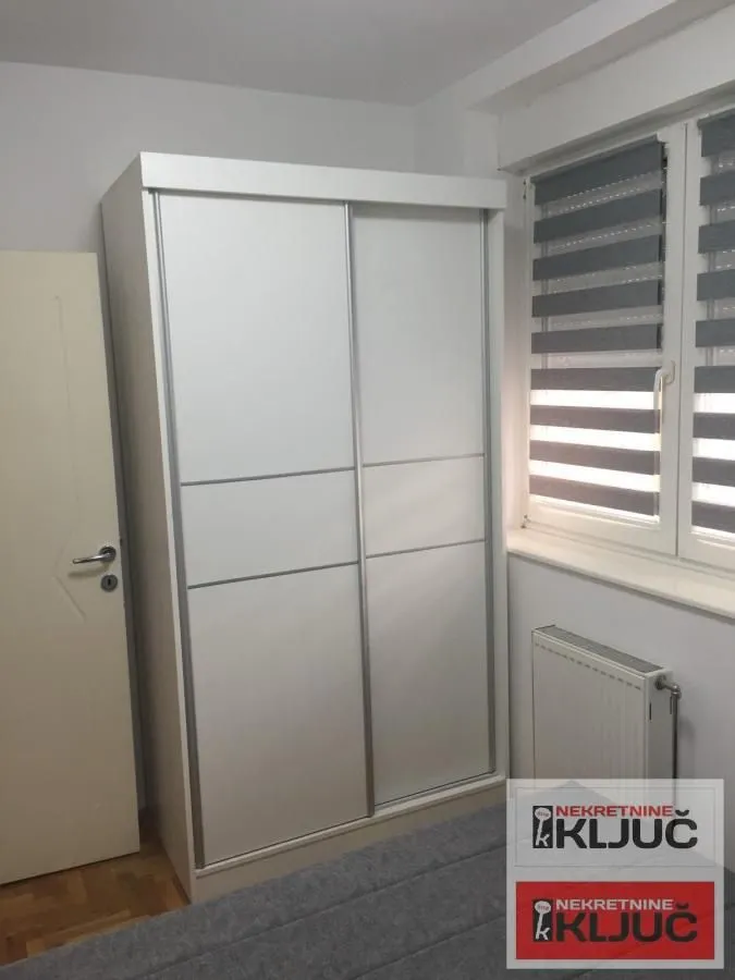 Spavaća soba sa velikim belim ormarom sa kliznim vratima.