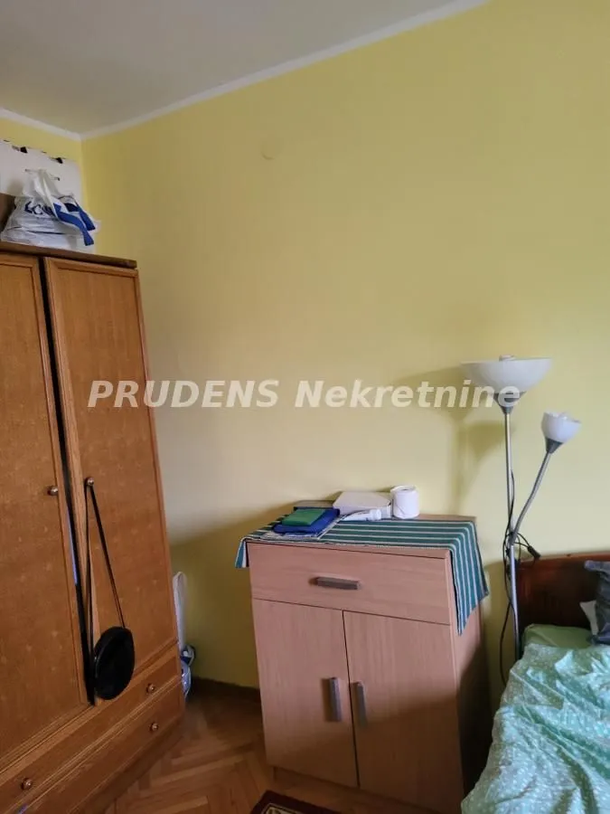 Spavaća soba sa drvenim ormanom, komodom i krevetom.