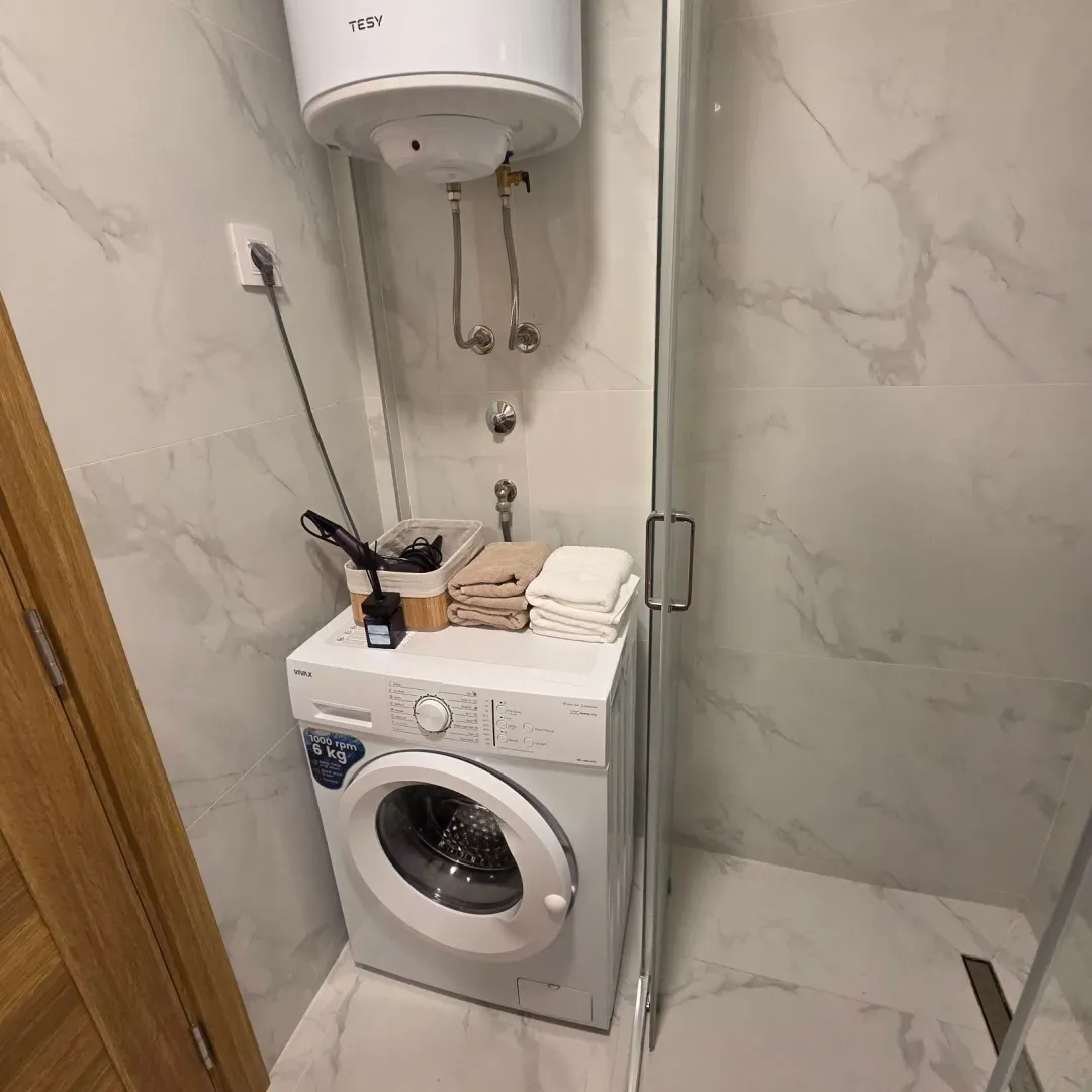 Modern bathroom with washing machine, water heater, and shower cabin.