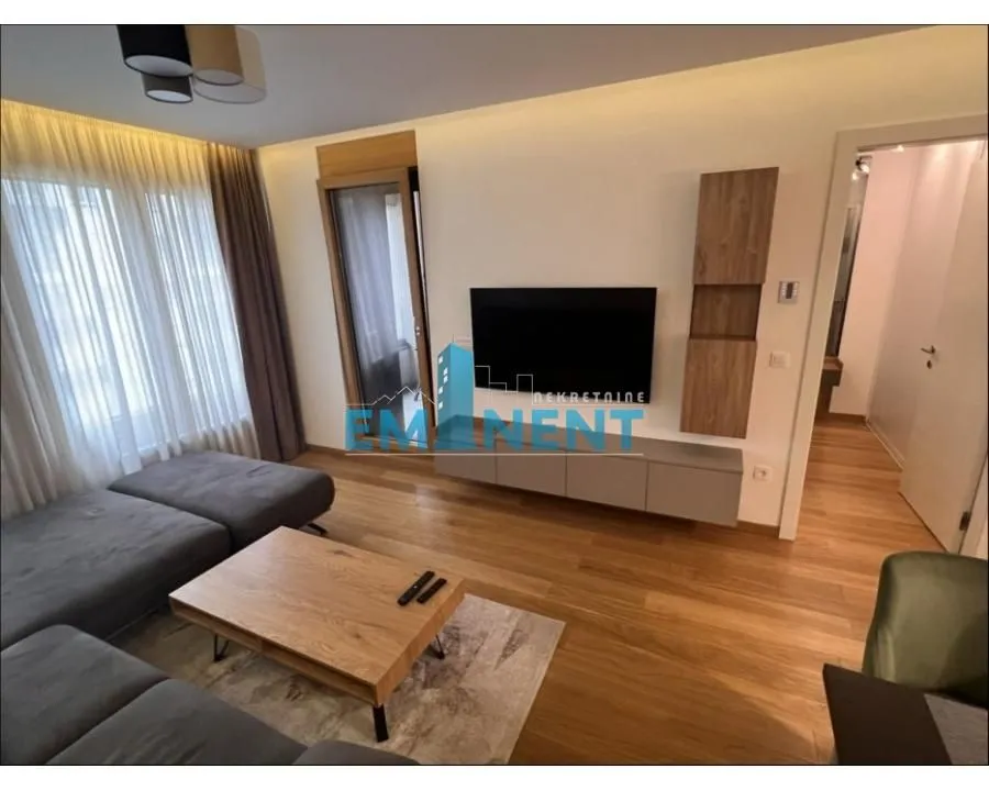 Living room with a sofa, TV, and wooden flooring.