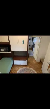 Small bedroom with a bed, wooden wardrobe, and parquet flooring. - image 3
