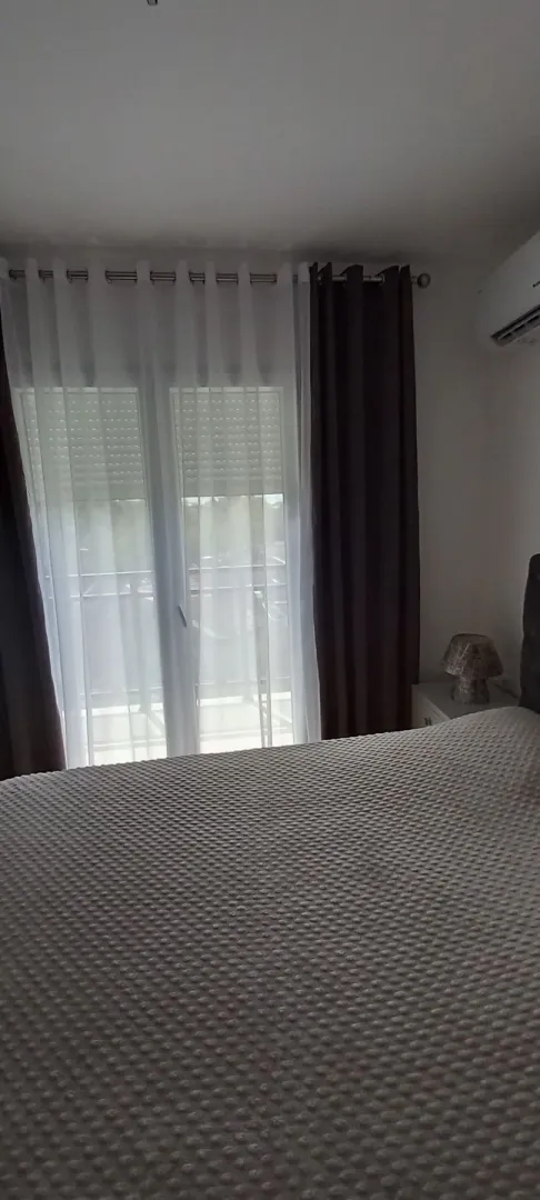 Simply furnished bedroom featuring a large bed and a window with curtains.