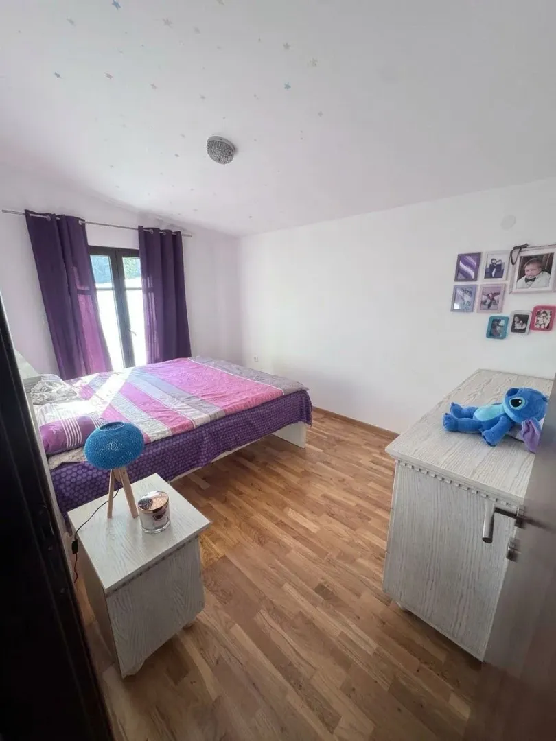 Bedroom with a double bed, dresser, and purple curtains.