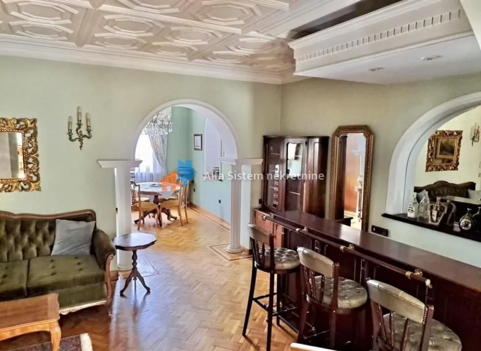 Living room with sofa, bar counter, and wooden flooring.