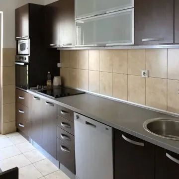 Kitchen with dark wooden cabinets, white countertop and ceramic wall tiles. - image 5