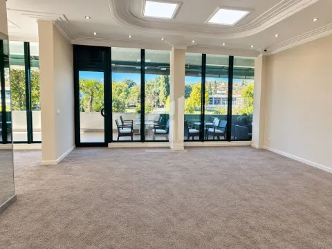 Spacious empty room with carpet, large glass surfaces, and a view of the terrace and greenery. - image 2