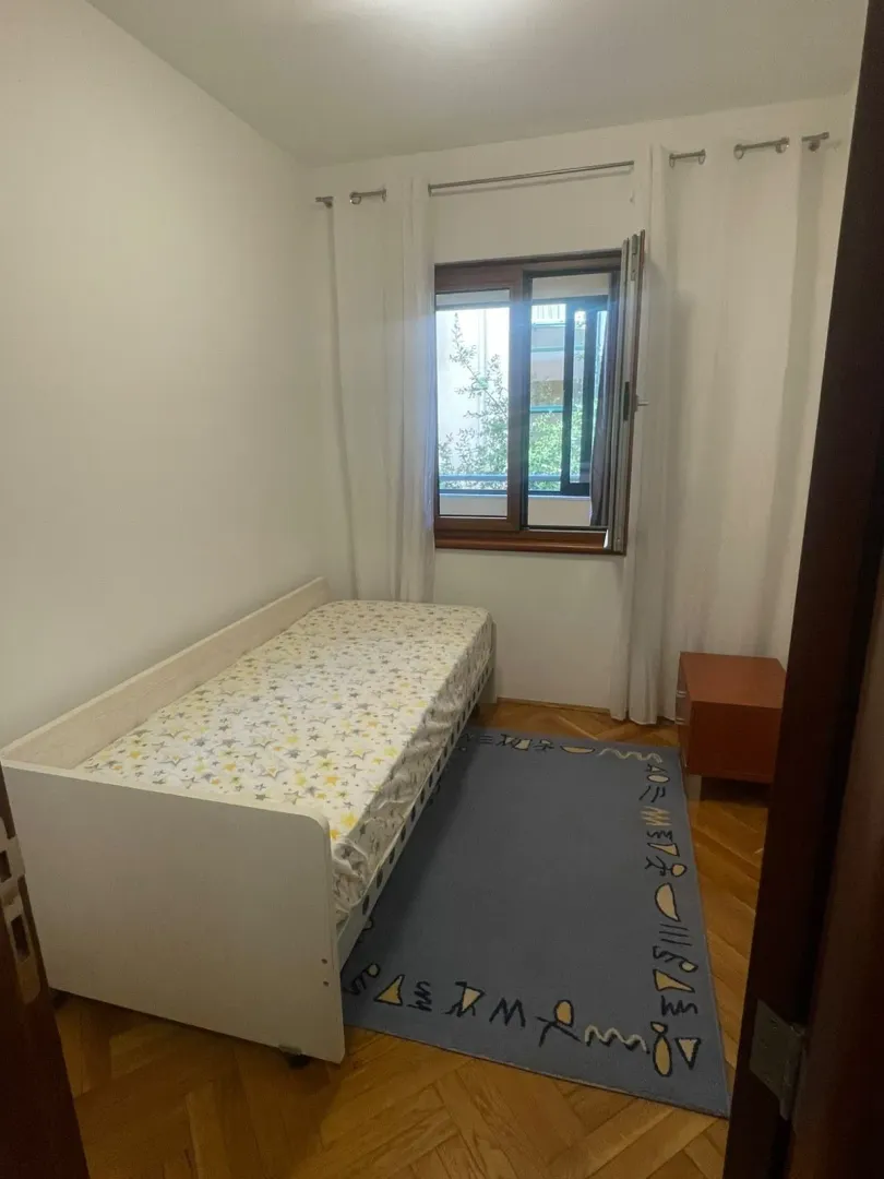Manja spavaća soba sa krevetom, tepihom i prozorom.