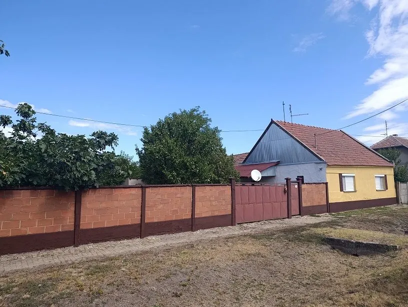 Pogled na spoljašnjost kuće sa ograđenim dvorištem i kapijom.