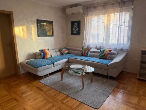 Living room with a sectional sofa, coffee table, and a window. - image 4