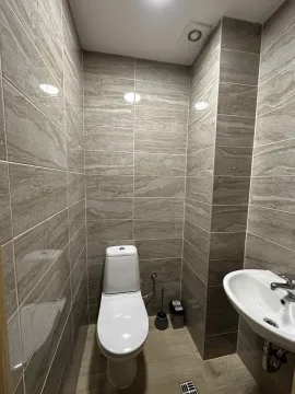 Manje kupatilo obloženo keramičkim pločicama sa toaletom i umivaonikom. - image 9