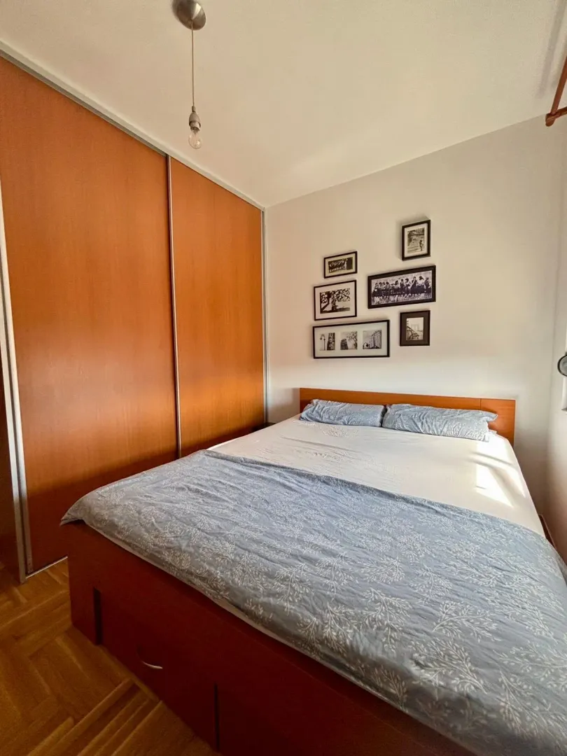 Furnished bedroom with a double bed and a large wooden wardrobe.