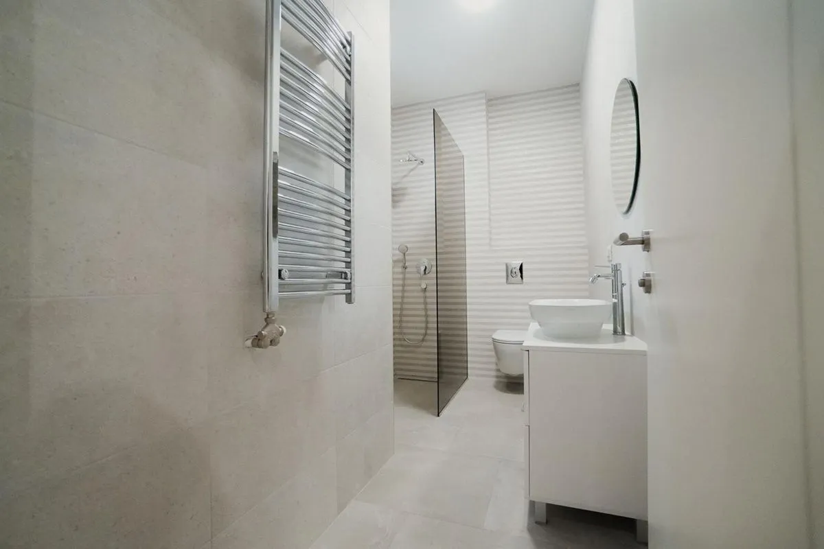 Moderno opremljeno kupatilo sa tuš kabinom, umivaonikom i WC šoljom.