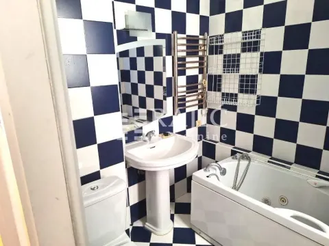 Manje kupatilo sa kadom, umivaonikom i wc šoljom, obloženo crno-belim pločicama. - image 3