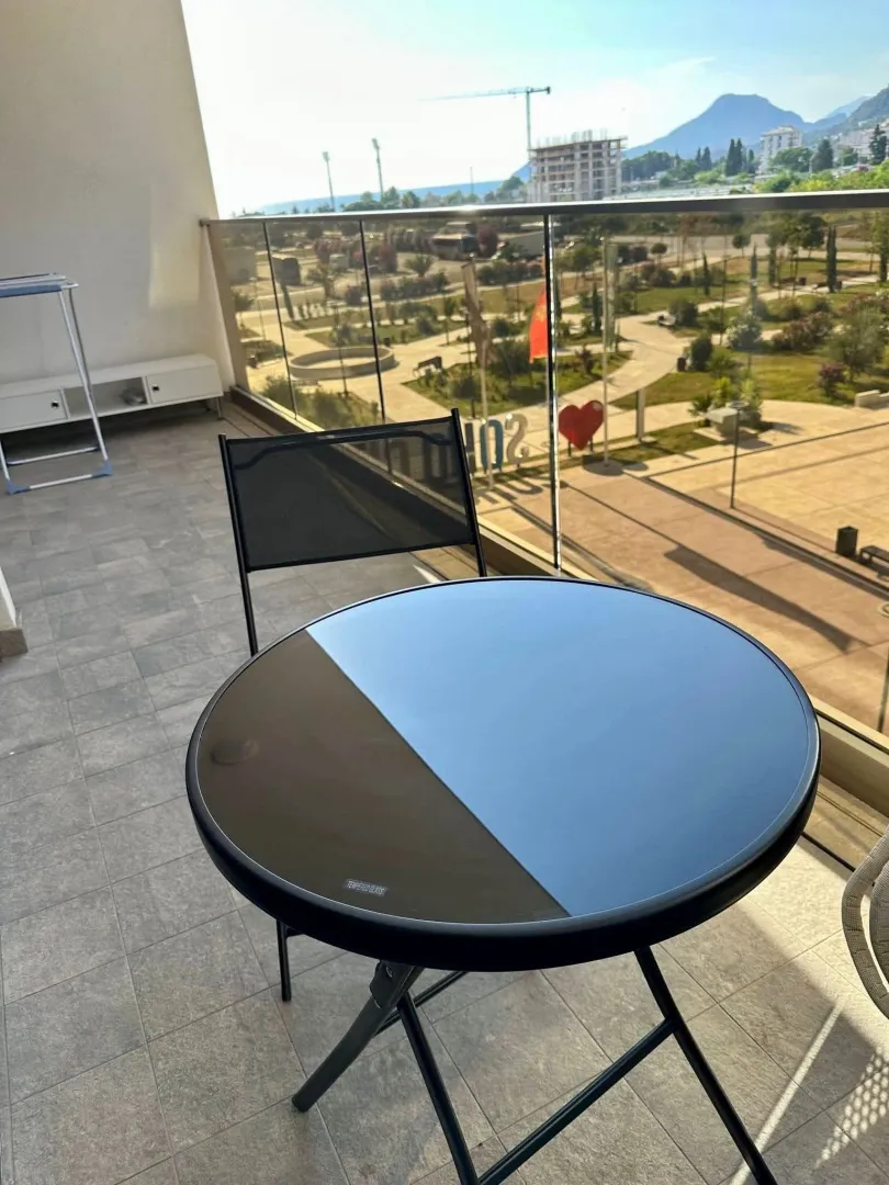 Spacious terrace with a table, chair, and a view of the park and surroundings.