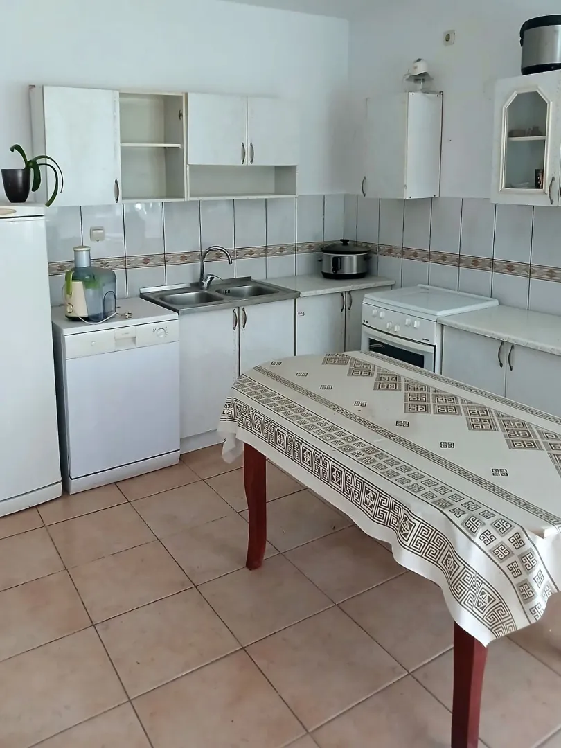 Older kitchen with a dining table and basic kitchen units.