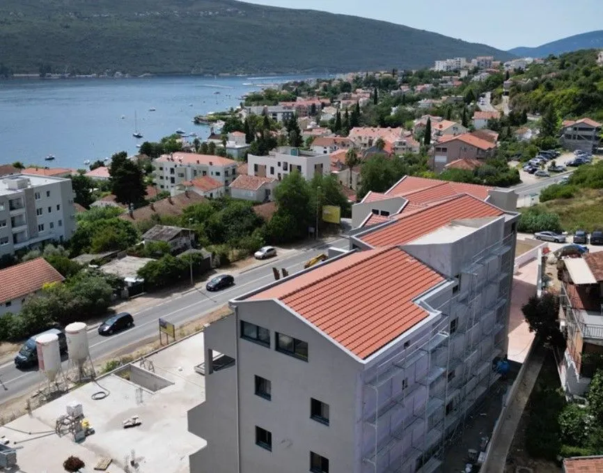 Pogled iz vazduha na stambenu zgradu u izgradnji sa okolinom i morem u pozadini.