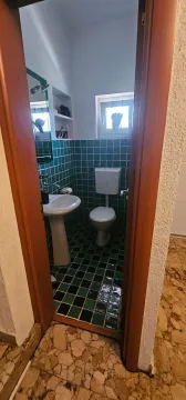 A view through the door into a bathroom with green tiles, a sink, and a toilet. - image 12