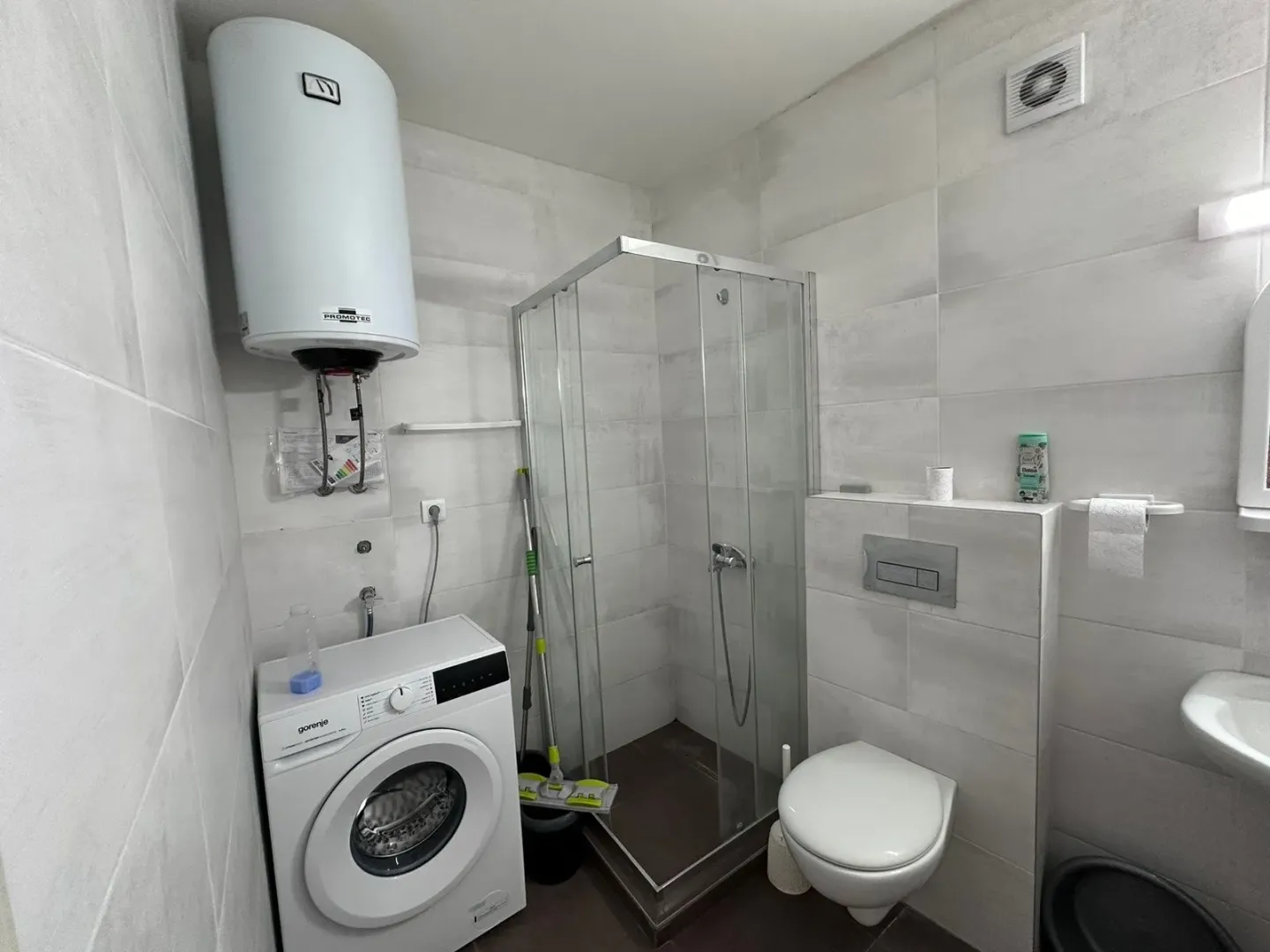 Smaller bathroom with a shower cabin, washing machine, and water heater.