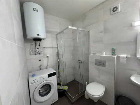 Smaller bathroom with a shower cabin, washing machine, and water heater. - image 7