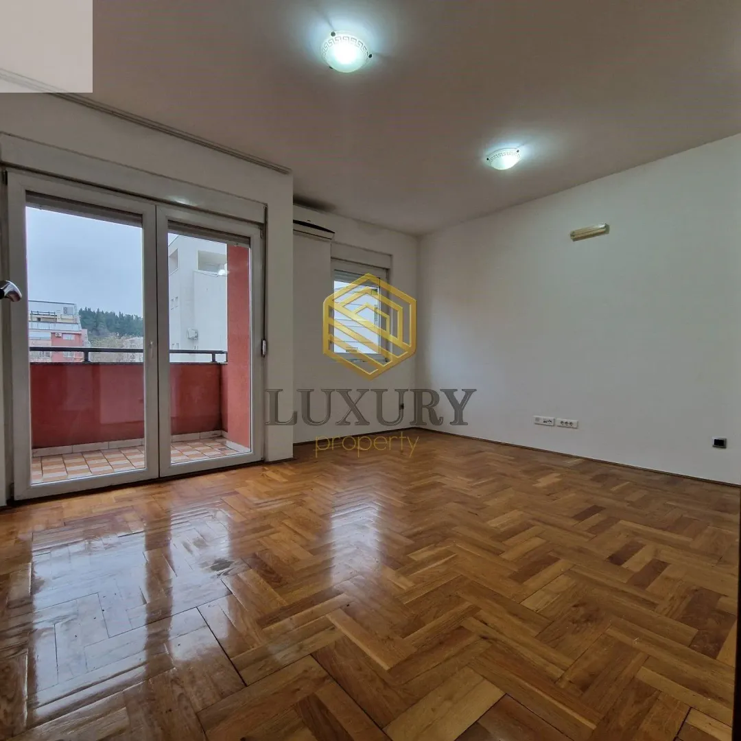 Empty room with parquet flooring and access to the balcony.