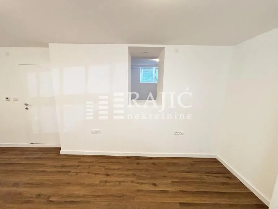 Empty room with white walls and wooden flooring.