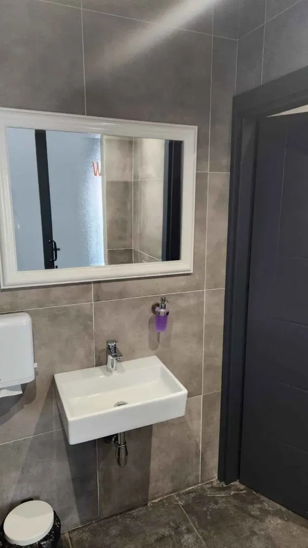 Small bathroom with a washbasin, mirror and grey ceramic tiles.