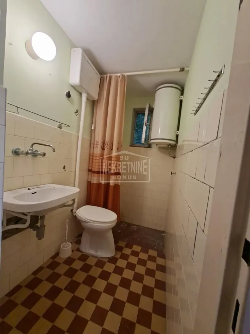 Manje kupatilo sa lavaboom, WC šoljom i tuš kabinom sa zavesom.
