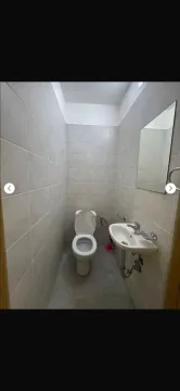 Smaller bathroom tiled with ceramic tiles featuring a toilet and a washbasin. - image 5