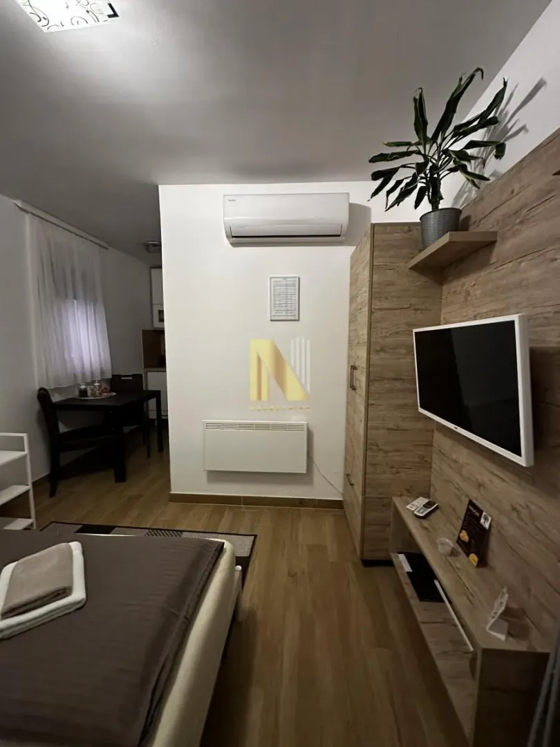 Furnished bedroom with a double bed, TV unit, and air conditioning.
