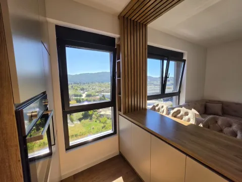 View from the kitchen with a breakfast bar and wooden decorative panels towards the window and living room. - image 3
