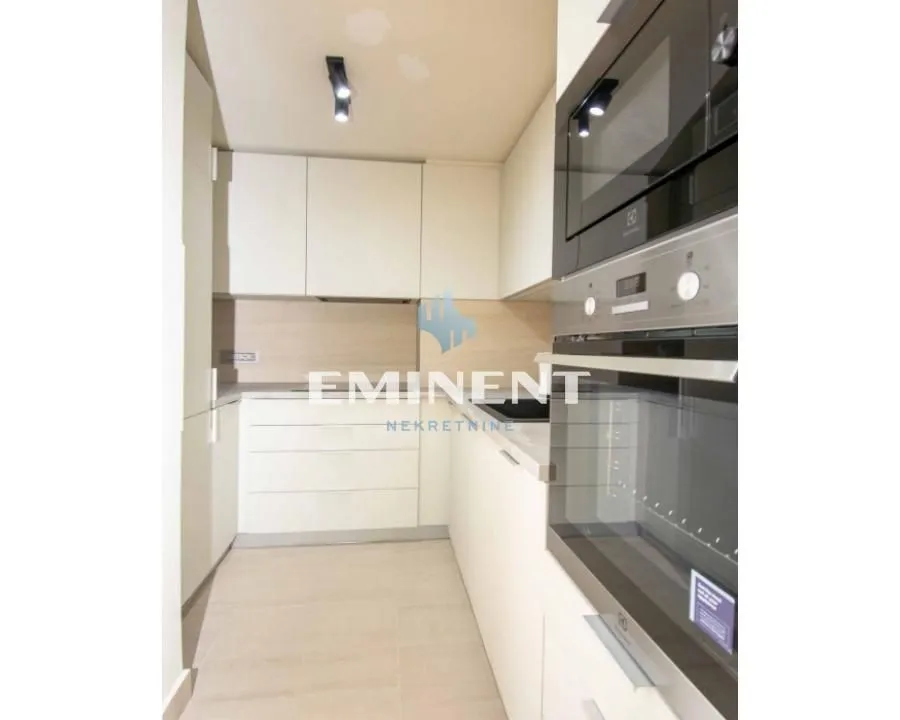 Modern kitchen with a built-in oven and light-toned cabinets.