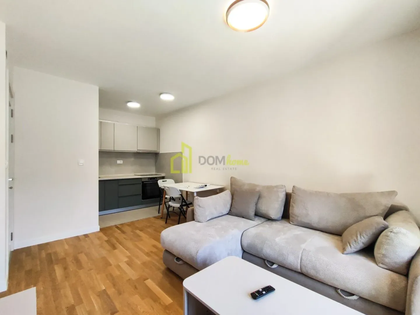 Living room with a sofa and dining area connected to the kitchen.