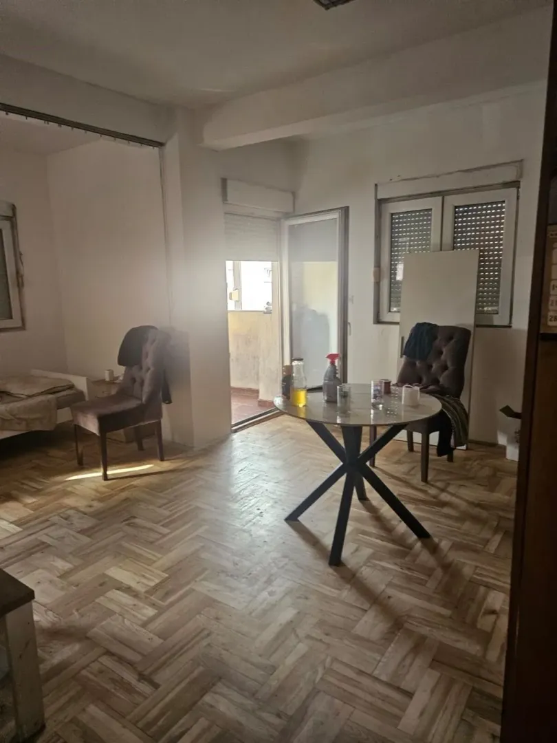 Dnevna soba sa trpezarijskim stolom, stolicama i parketom na podu.