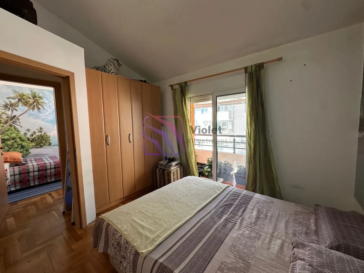 Namještena spavaća soba sa bračnim krevetom, garderoberom i izlazom na terasu.