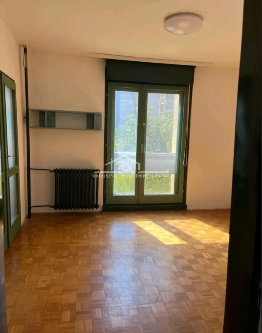 Empty room with parquet flooring and balcony doors.