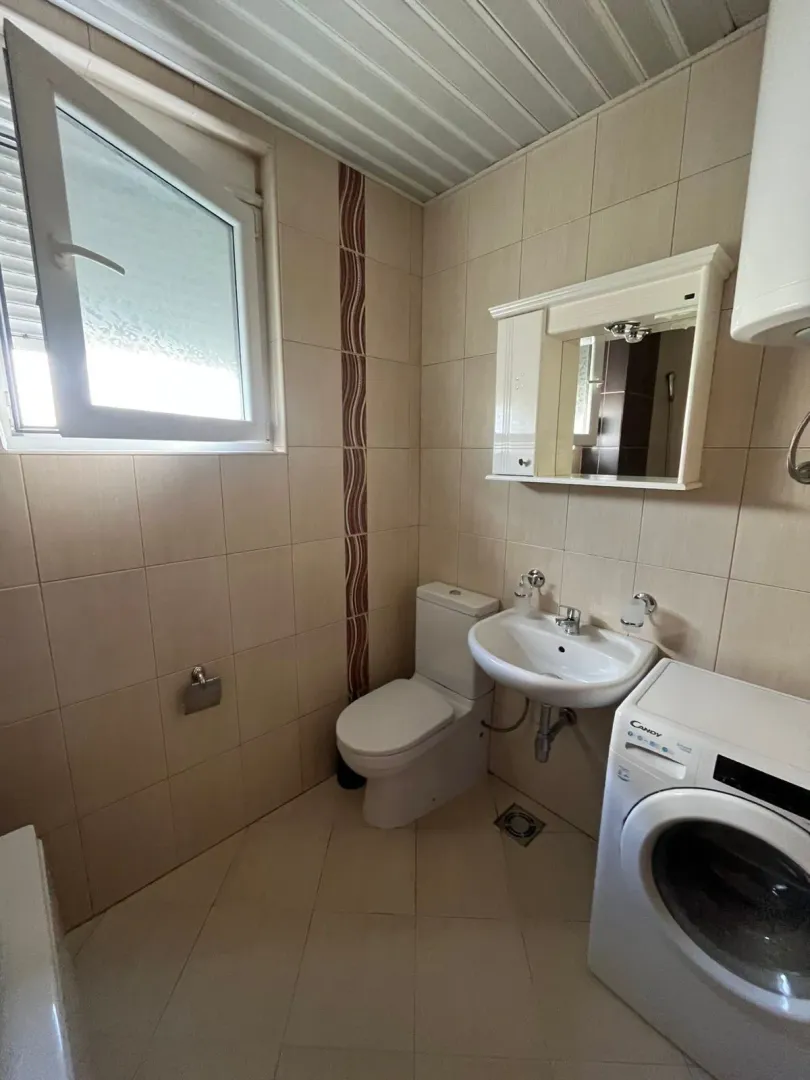 Small bathroom with sanitary fixtures, a sink, and a washing machine.