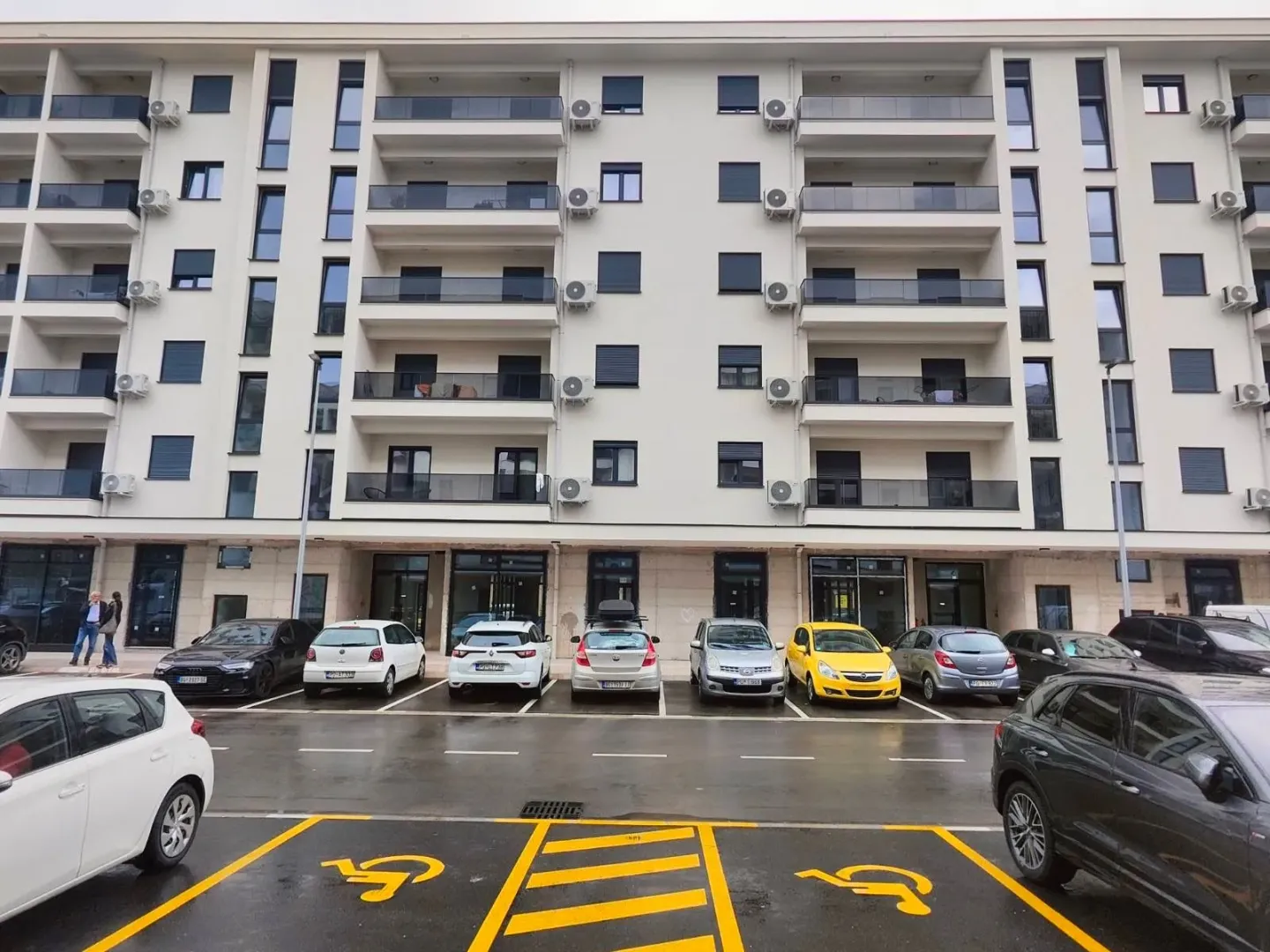 Fasada i parking ispred stambene zgrade.