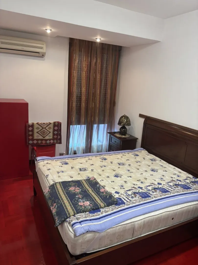 Simply furnished bedroom featuring a double bed and striking red flooring.