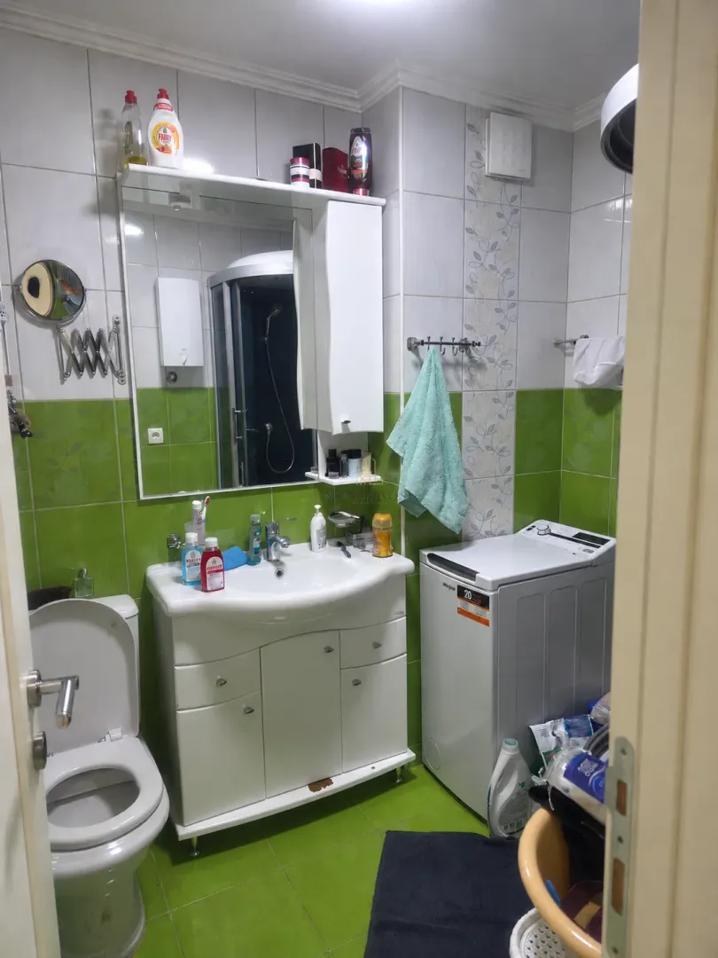 Kupatilo sa umivaonikom, WC šoljom, tuš kabinom i mašinom za veš.