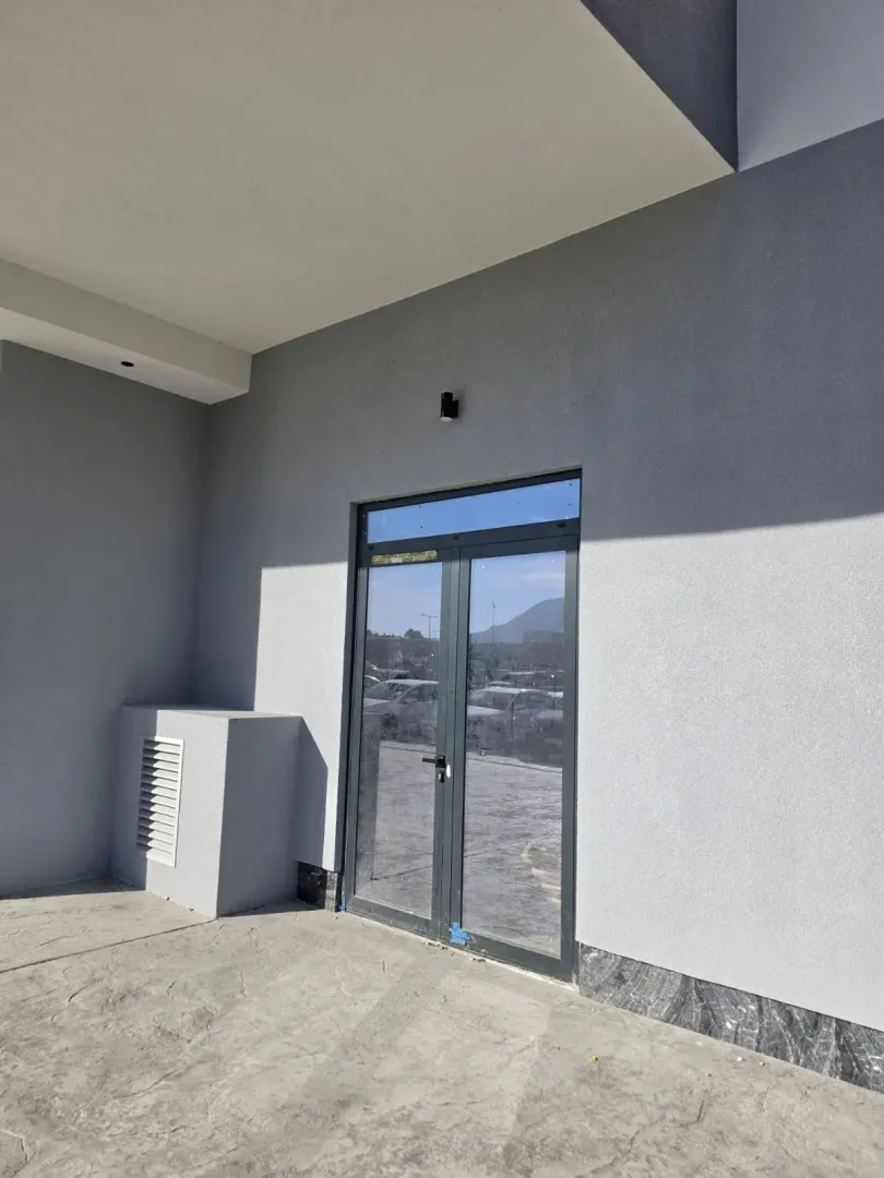 Exterior entrance to a commercial space with glass doors and a grey facade.