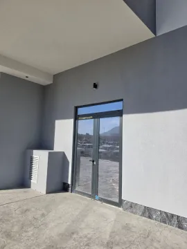Exterior entrance to a commercial space with glass doors and a grey facade. - image 2