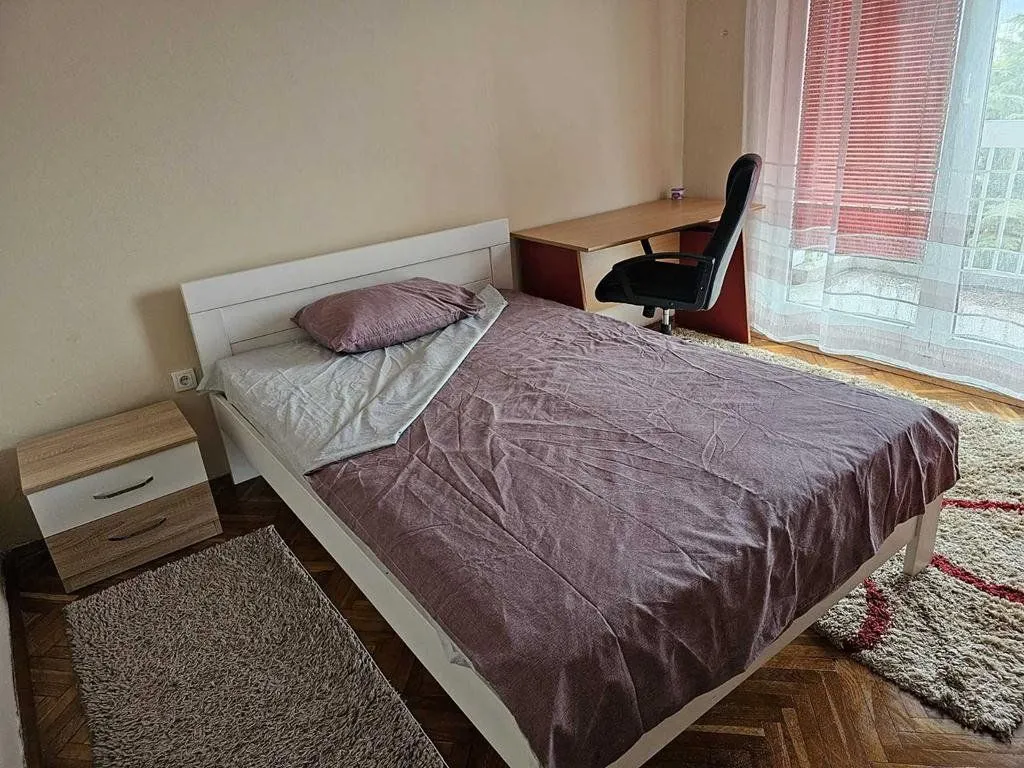 Namještena spavaća soba sa bračnim krevetom, radnim stolom i noćnim ormarićem.