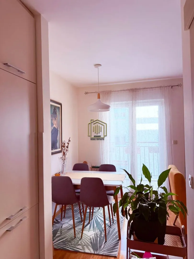 Trpezarija sa stolom, stolicama i izlazom na balkon.