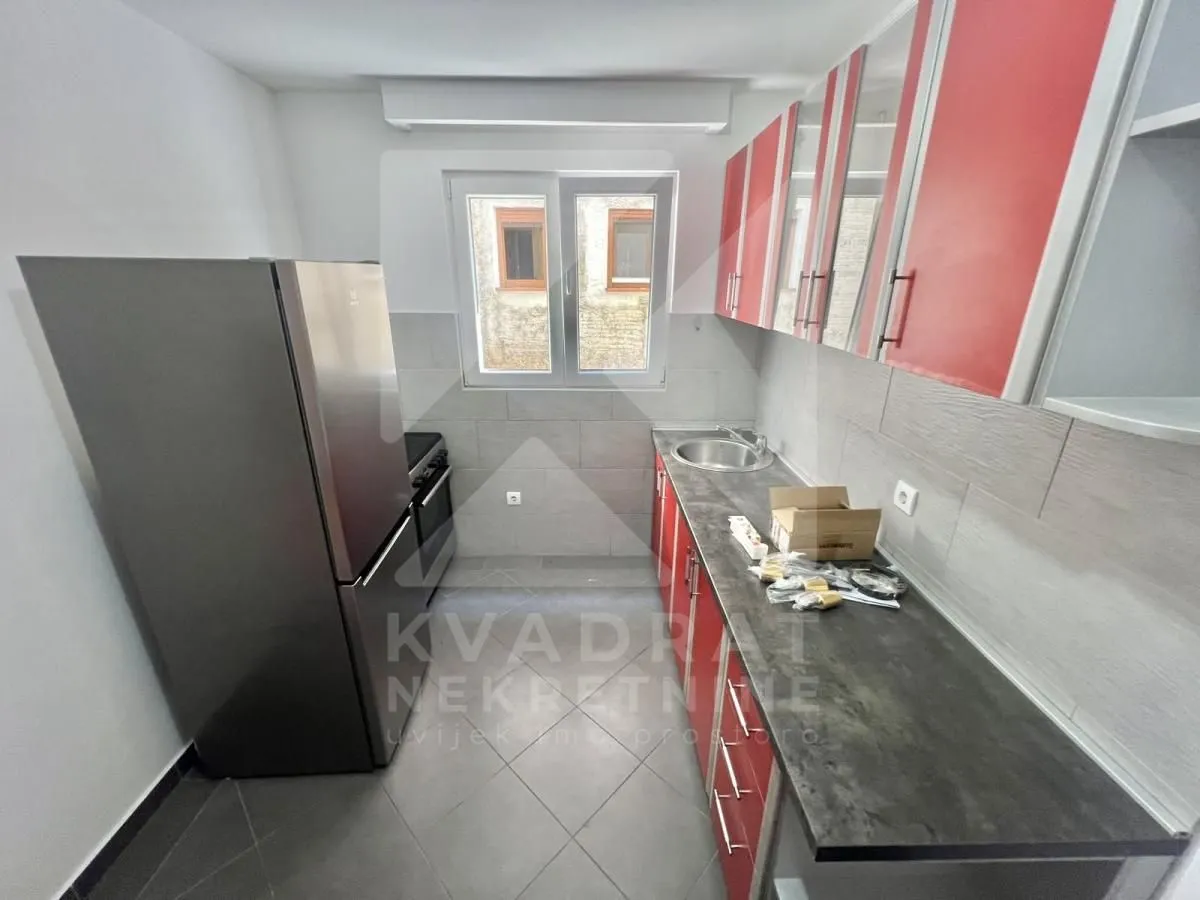 Small kitchen with red cabinets, a refrigerator, and a window.