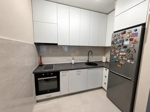 Moderna kuhinja sa bijelim elementima i tamnom radnom površinom. - image 6