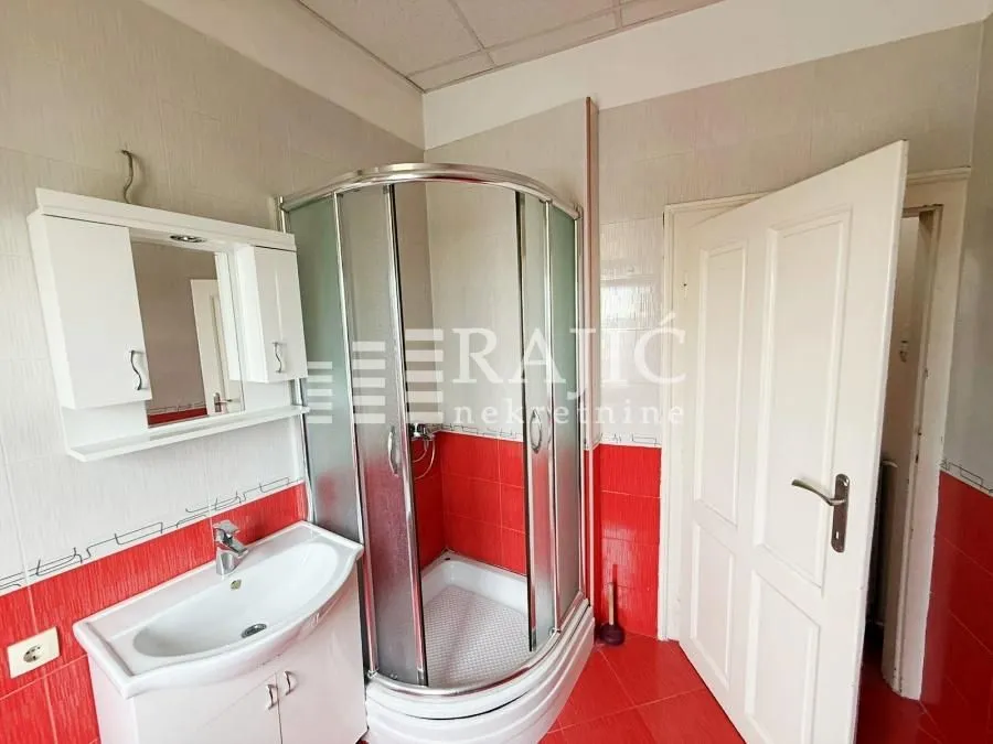 Small bathroom with a shower cabin, washbasin, and white tiles.