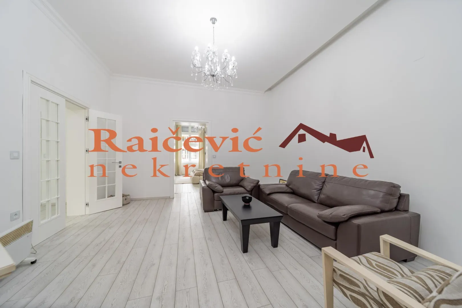 Spacious living room with leather furniture and white laminate flooring.