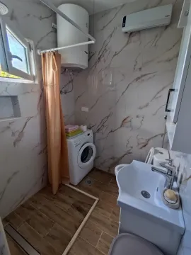 Kupatilo sa mermernim pločicama, umivaonikom, veš mašinom i tuš kabinom sa zavesom. - image 10