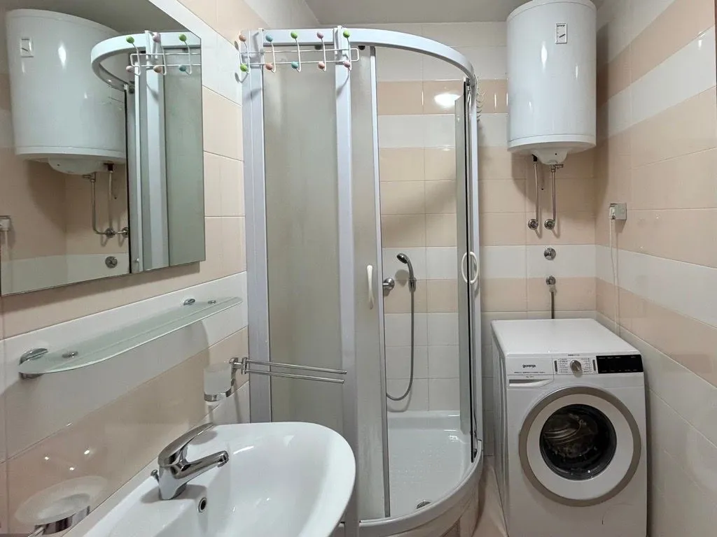 Small bathroom with a shower cabin, washbasin, and washing machine.