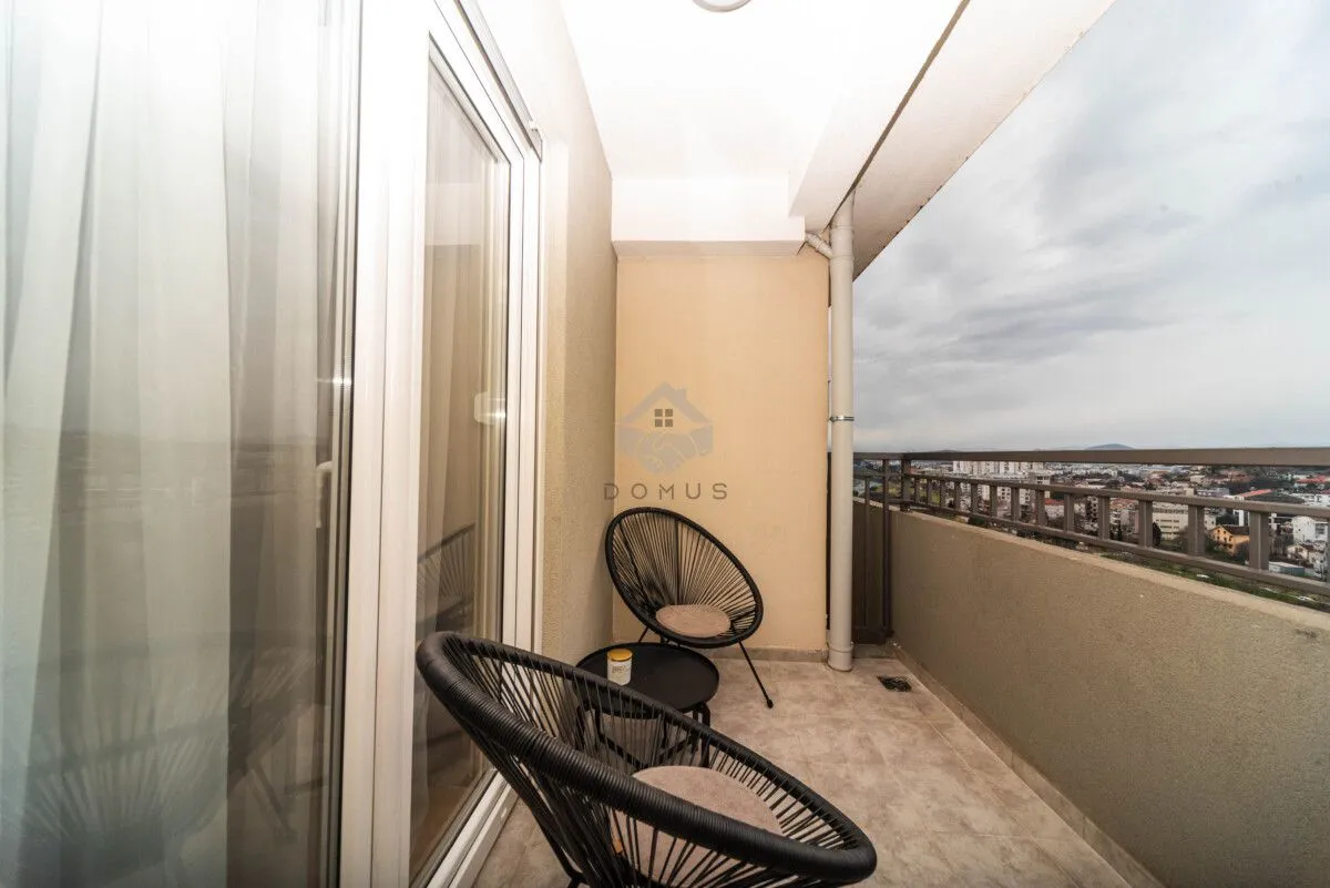 Natkriveni balkon sa garniturom za sjedenje i pogledom na grad.